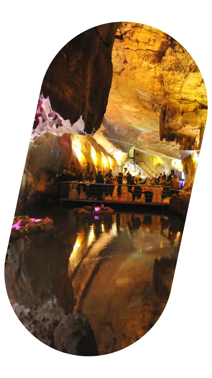 Dinner inside a cave lit in gold, tables beside the water.