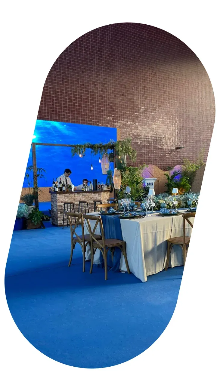 An event room with blue carpet, tables laid and a large screen at the far end.