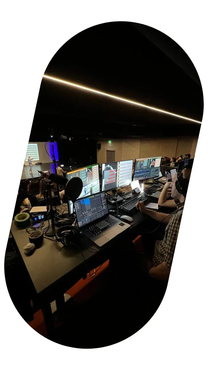 A gallery desk with several monitors lit, in a dark room during an event.