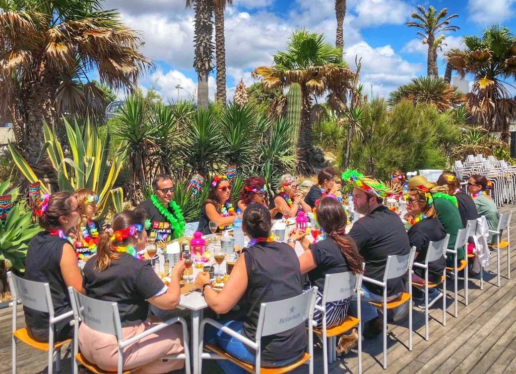 Lunch outdoors on a terrace among palm trees, with colourful garlands and a blue sky.