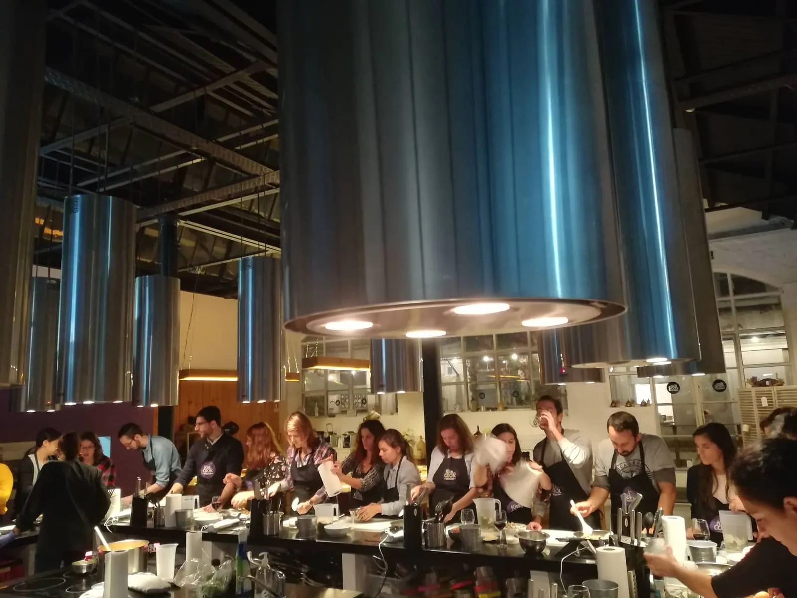Dinner in a high-ceilinged industrial space, columns of blue light between the tables.