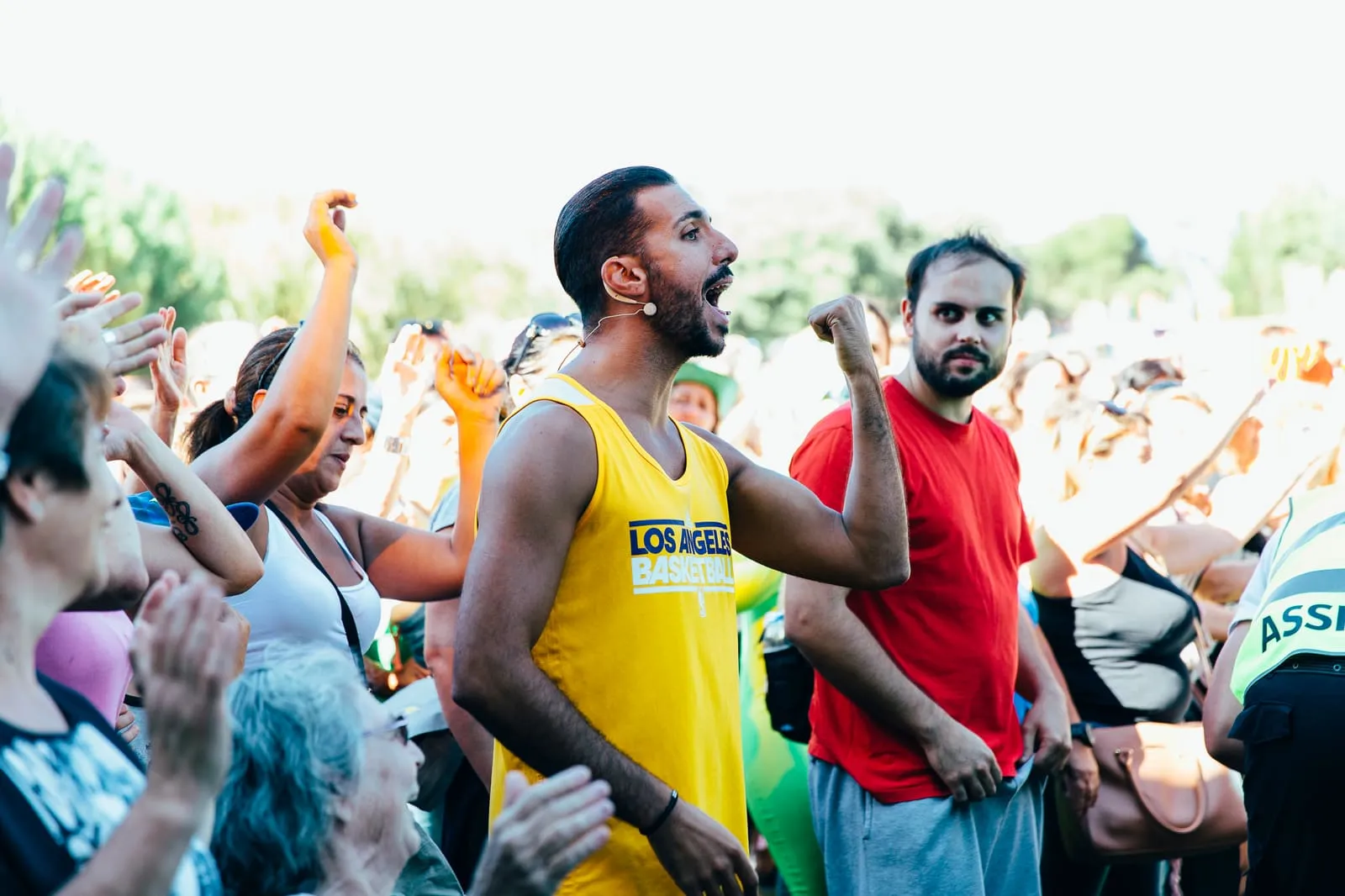 Grupo a festejar ao ar livre com os braços no ar, num dia de sol.