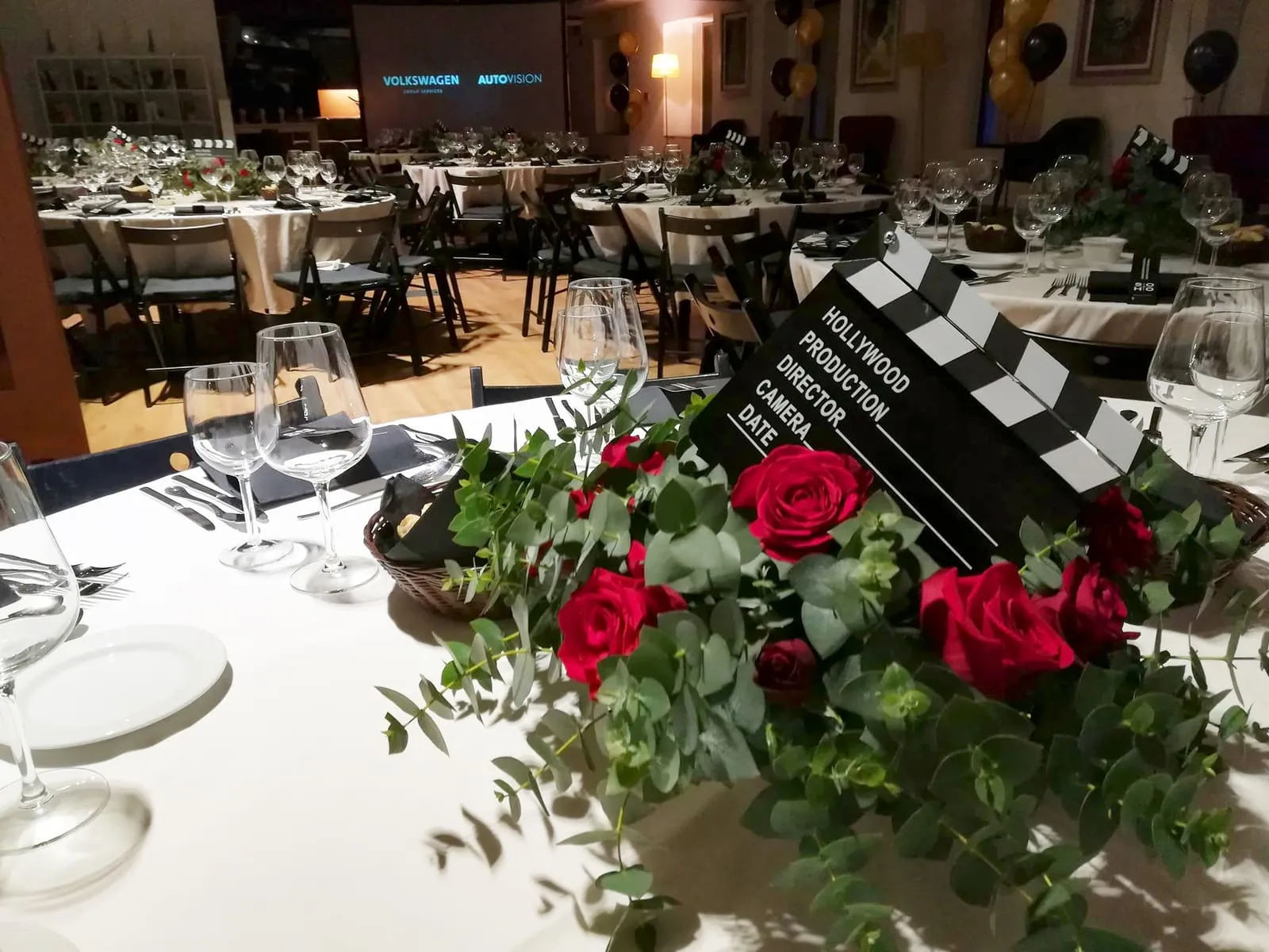 A table set with red roses and a film clapperboard resting between the plates.