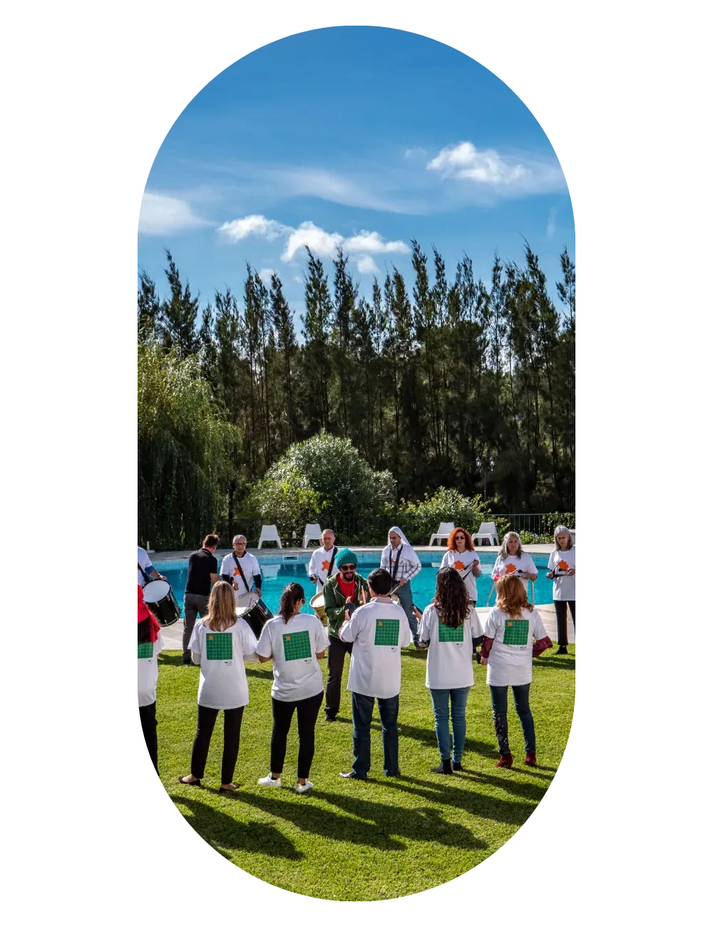 A team in white shirts standing in a circle on the grass, under a clear sky.
