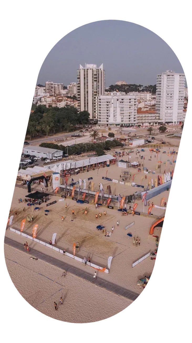 Vista aérea de uma praia com uma estrutura de evento montada junto à água.