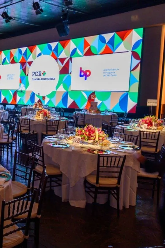 A conference dinner with dressed tables and the event screen at the back.