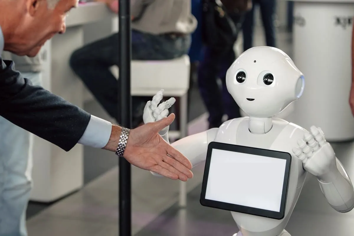 A reception robot greeting a guest with a handshake.